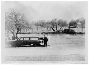 Primary view of object titled '[Army Helicopter Hovering Near a Station Wagon]'.