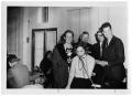 Photograph: [People Standing Around a Woman Speaking on a Telephone]