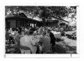 Photograph: [People Seated Around Picnic Tables]