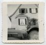 Thumbnail image of item number 1 in: '[Photograph of a House Taken in Front of a Vehicle's Hood]'.