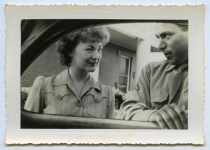 [A Man and Woman Stand Next to a Car]