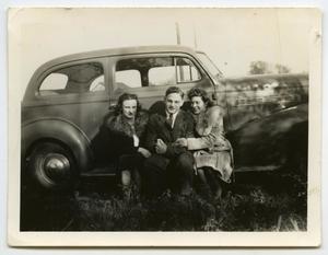 [Photograph of a Man and Two Women near a Car]