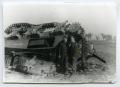 Photograph: [Two Soldiers Standing in Front of an Overturned Tank]