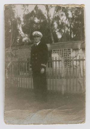 [Photograph of a Navy Officer by a Fence]
