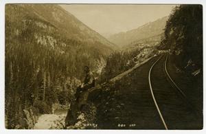 [Postcard of Man Sitting on Railroad Track Cliff]