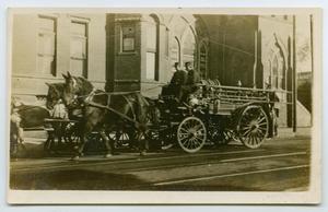 Primary view of object titled '[Postcard with a Photograph a Horse-Drawn Fire Wagon Rolling Down a Street]'.