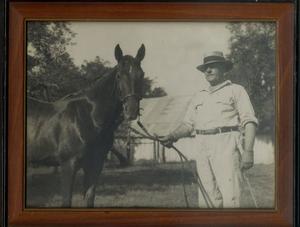 [Framed picture of a man with glasses holding a horse by the reins]