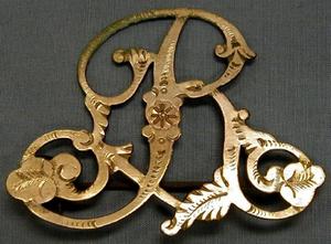 [Bronze pin, monogram "R", presumably for Ryon]