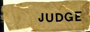 [Beige silk ribbon that states: "JUDGE"]