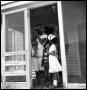 Photograph: [Woman Standing in a Porch Doorway with Children]