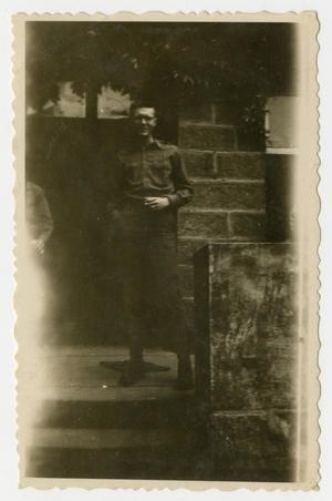 Primary view of object titled '[Photograph of a Soldier Standing by a Brick Building]'.
