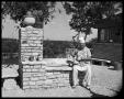 Photograph: Dewey Bradford seated beside barbecue grill