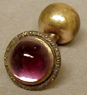 [One of a pair of gold cuff link with a purple jewel]