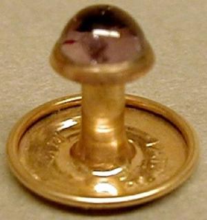 [One of a pair of gold cuff links with a purple jewel mounted on top]
