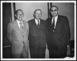 [Photograph of three men standing in a room]
