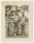 Photograph: [Photograph of Three Men in Uniforms and a Baby Posing Outside]