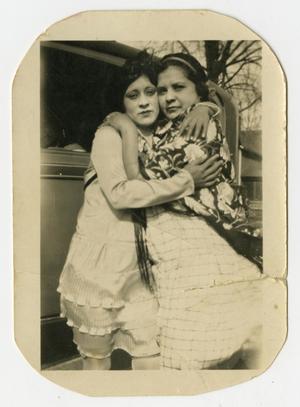 [Photograph of Two Woman Hugging by an Automobile]