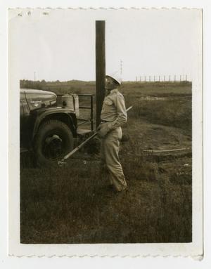 [Man Standing by Pole and Vehicle]