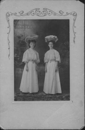 [Two young women standing in long white dresses]
