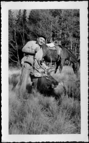 [Photograph of a man holding the horns of an elk killed in a hunt]