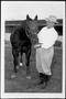 Photograph: [Photograph of a man holding the halter on a King Ranch owned horse]