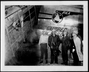 [Photograph of five men standing near an airplane]