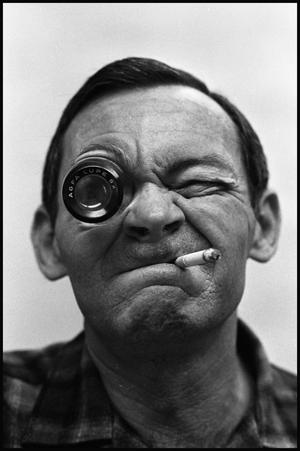 Primary view of object titled '[Photograph of George Smiley Smoking Cigarette and Wearing Eye Ornament]'.