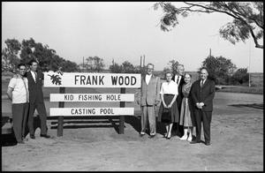 Primary view of object titled '[Frank Wood and Group Pose Around Fishing Pond Sign]'.