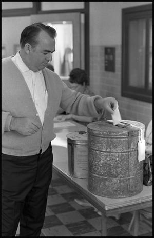 [Man Depositing His Ballot in Container]