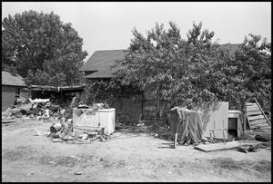 Primary view of object titled '[Impoverished Wooden House With Junk in Yard]'.