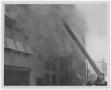Photograph: [Firefighter's Ladder Extending Towards Smoking Building]