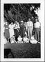 Photograph: [Family standing in a yard in front of a large tree]
