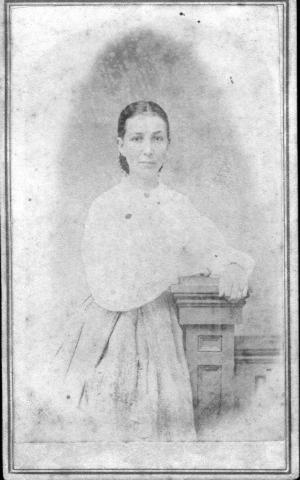 [A young woman leaning against a waist high post]