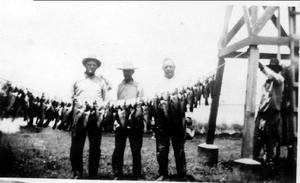 [A.P. George and three men standing behind a string of fish]