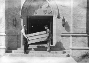 Primary view of object titled '[Two Men Carry a Crate into Shelton Chapel]'.
