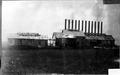 Photograph: [An industrial factory with twelve smoke stacks protruding from the t…