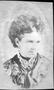 Photograph: [Bust photograph of a woman wearing a dark printed top and a scarf ar…