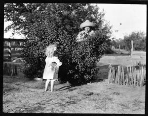 [Photograph of Woman and Child Playing in Bushes]