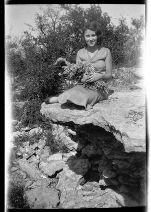 [Photograph of Young Woman with Wildflowers on Rock]