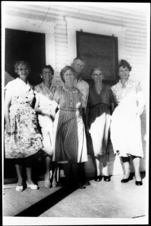 [A group of older adults standing on a porch]