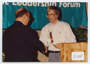 Primary view of object titled '[Photograph of Dr. Duane M. Leach Shaking James Shelton's Hand]'.