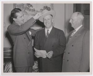 Primary view of object titled '[Photograph of Man Putting Cowboy Hat on Another Man's Head]'.