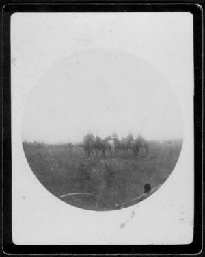 [Photograph of five people on horseback in a pasture]