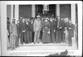 Photograph: [A large group of men standing around a couple]