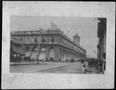 Primary view of [A city street scene near the corner of a two story stucco building]