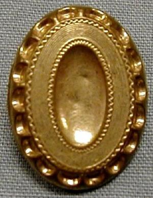 [Oval shaped brass button with depression in center]