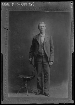 [Portrait of Man in Suit Standing Beside Chair]
